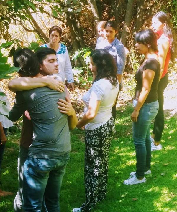 Participantes acompañan un abrazo en el jardín