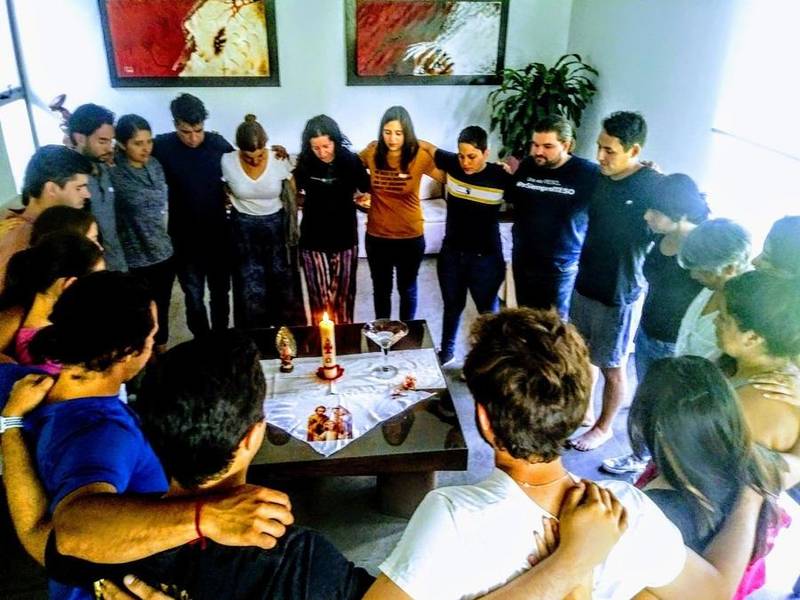 Grupo reunido en oración alrededor de una vela
